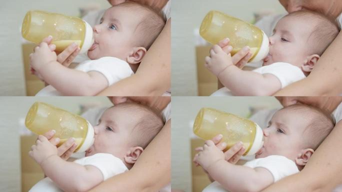 婴儿男孩在母亲的腿上奶瓶喂养