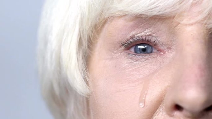 眼泪从悲伤的老妇人的脸颊流下，眼睛放电，流泪缓慢-mo