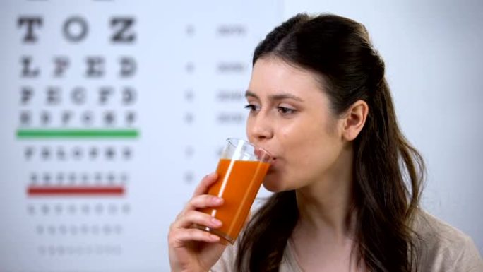 快乐的女人喝健康的新鲜胡萝卜汁，背景图，视觉