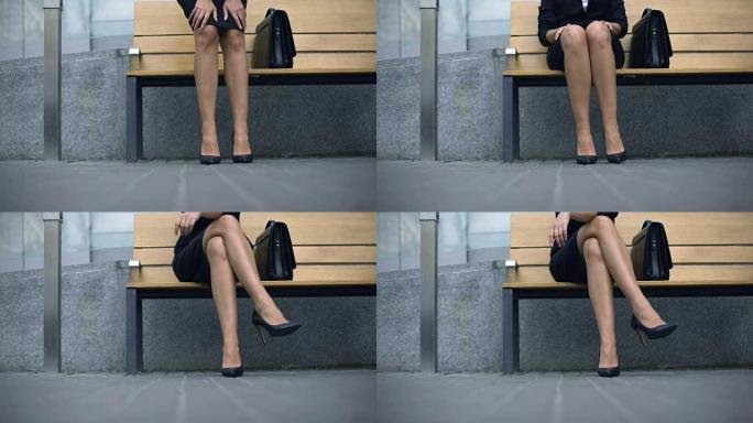 女士坐在长凳上，期待客户，厌倦了站在高跟鞋上