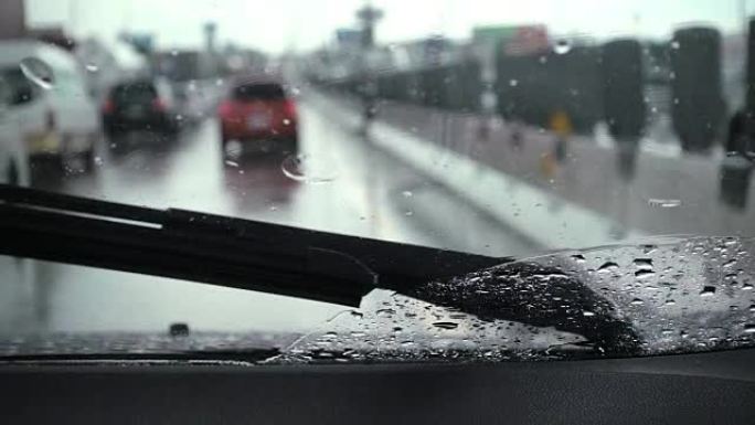 汽车雨刮器正在缓慢清除雨水并在道路上行驶