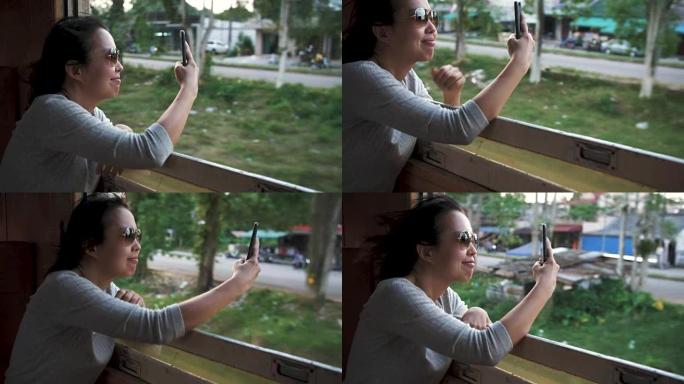 女旅行者在火车上用手机拍照