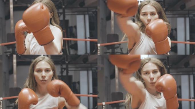 美丽的女拳击手拳击相机肖像。迷人的年轻苗条的高加索女人在拳击场上的健身房里挥拳的特写镜头。性别平等概