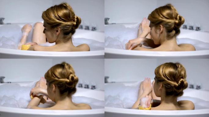 少女在沐浴用海绵清洗身体，日常美容程序，后视图