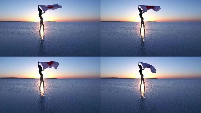 美丽的芭蕾舞演员在水上举着一面日本国旗。有风的一天。慢动作