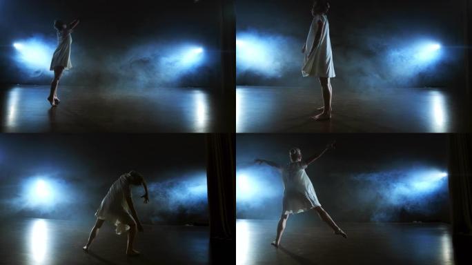 穿着白色连衣裙的现代舞女人在舞台上跳现代芭蕾舞，跳，在蓝色聚光灯下用烟雾旋转。