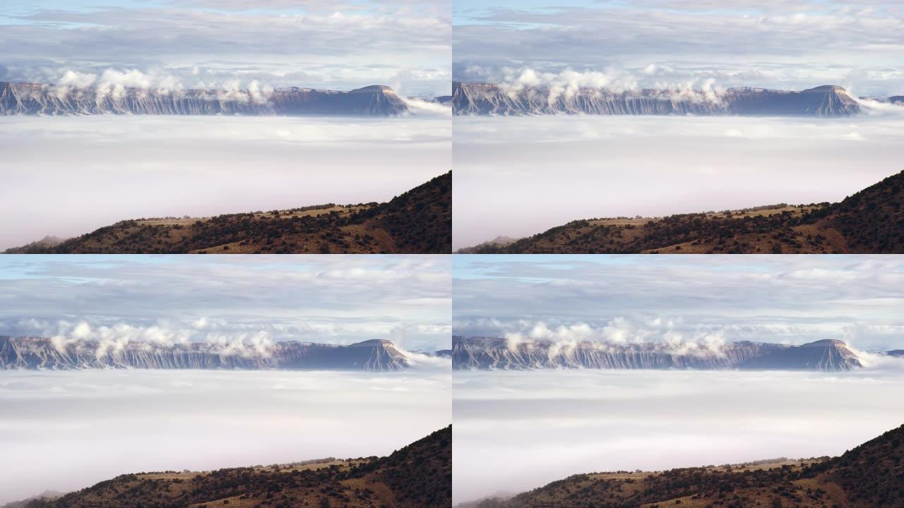 乌云/雾反转的时间间隔在科罗拉多州西部的大山谷上，背景是书本悬崖和加菲猫山