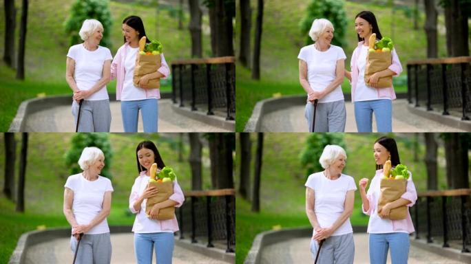 孙女带食物给老年女病人，在医院公园散步