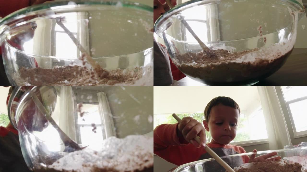 一个可爱的六岁白人男孩在室内厨房烘烤时，用木勺在一个大玻璃碗中混合配料