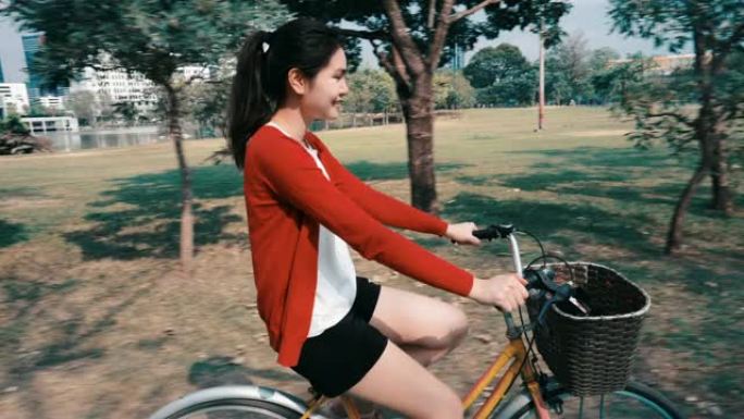 美丽的女孩，她快乐地在公园的自行车道上骑自行车。