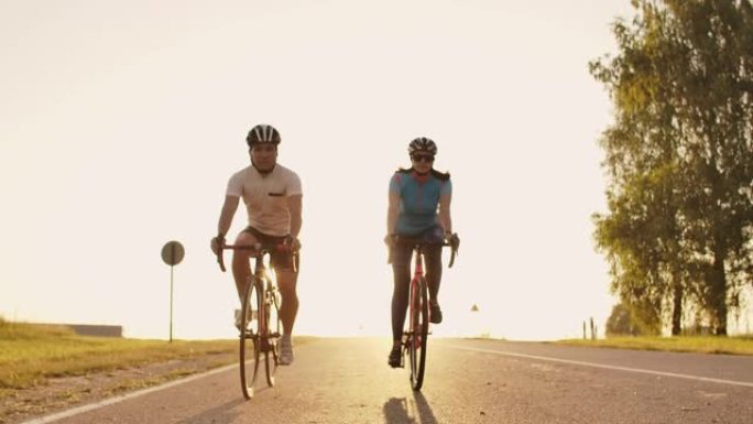 一名男子和一名女子在日落时在高速公路上骑运动自行车，装备和防护头盔慢动作120 fps