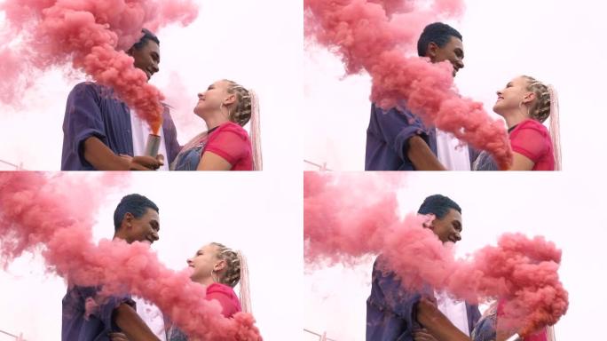 年轻的多民族夫妇拥抱在粉红色的烟雾，浪漫，慢动作中