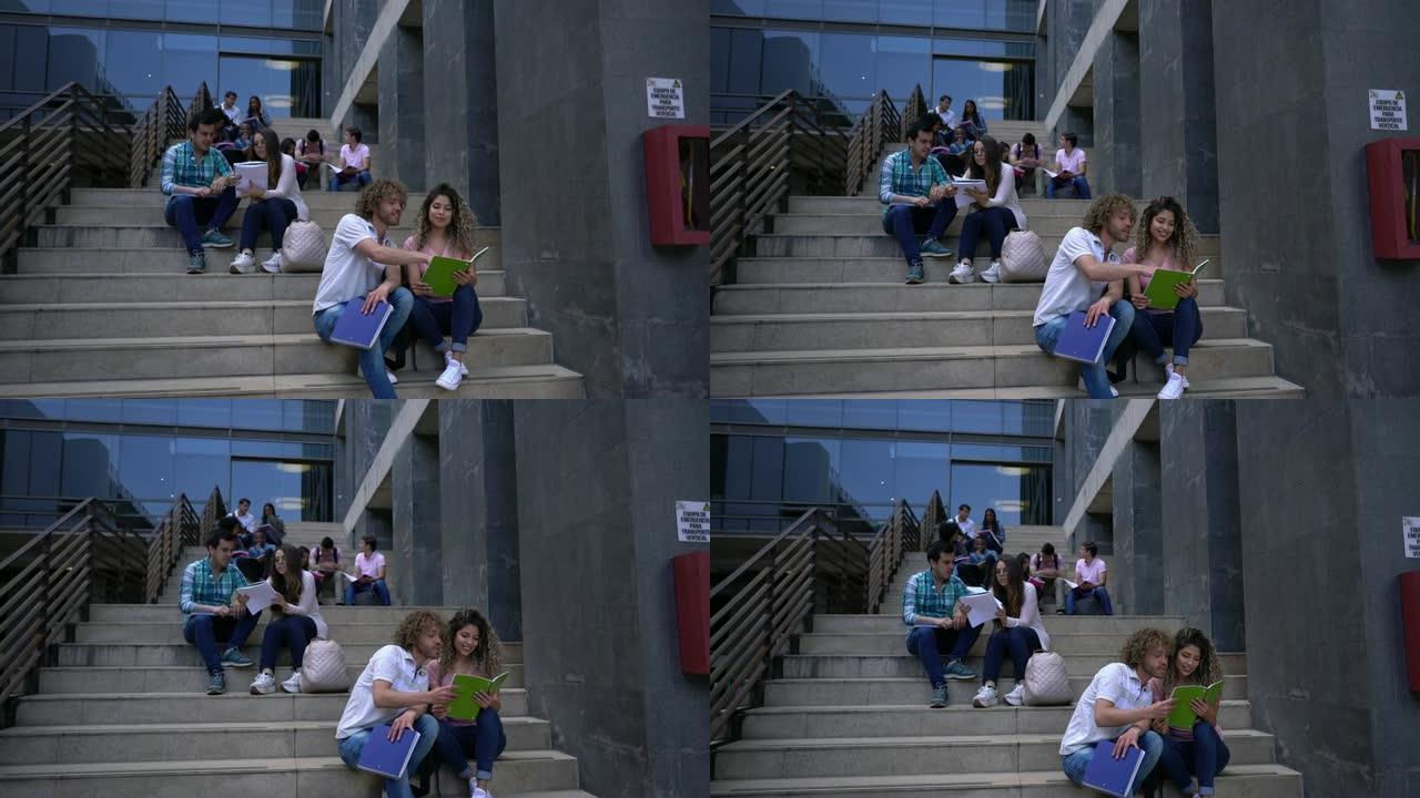 大学里的学生们坐在楼梯上分组或情侣学习