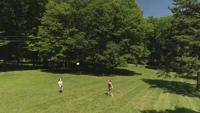 十几岁的女孩和年轻的女人在草坪上打排球。低空空中无人机视频