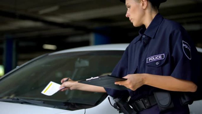 女警察写交通罚单并戴上挡风玻璃，违章停车