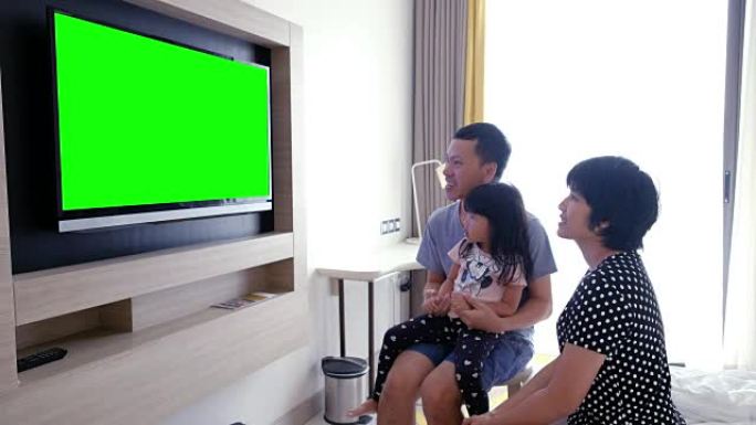 父母和女儿看Chromakey电视