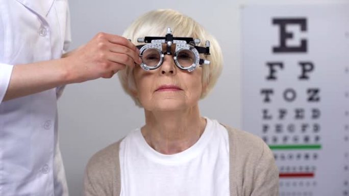 配镜师为光学试验架中的高级女性选择正确的镜片，检查