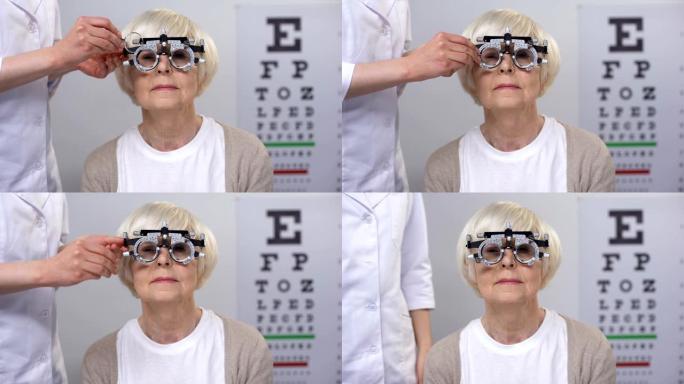 配镜师为光学试验架中的高级女性选择正确的镜片，检查