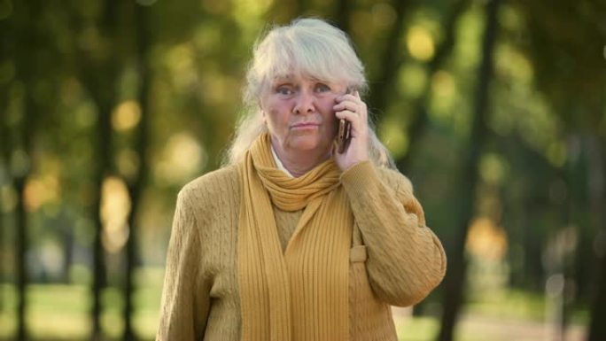 悲伤的高级女士在公园里用手机聊天，孤独，没有家人和朋友