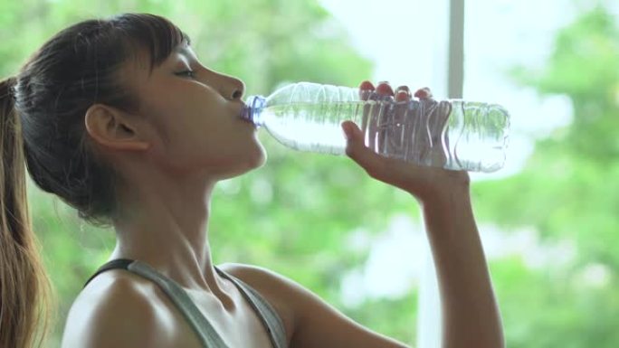 年轻健康的女人用塑料瓶喝水
