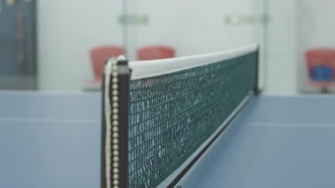 乒乓球飞行的乒乓球网特写。不知名的人在室内健身房玩体育游戏。