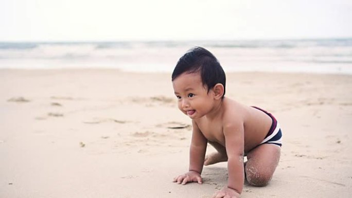 亚洲男婴爬行并坐在泰国Petchaburi的Cha Am海滩。