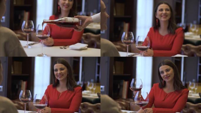 服务员在餐厅的女孩的杯子里倒红酒