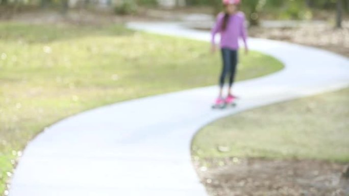 女孩在公园里朝摄像机骑滑板