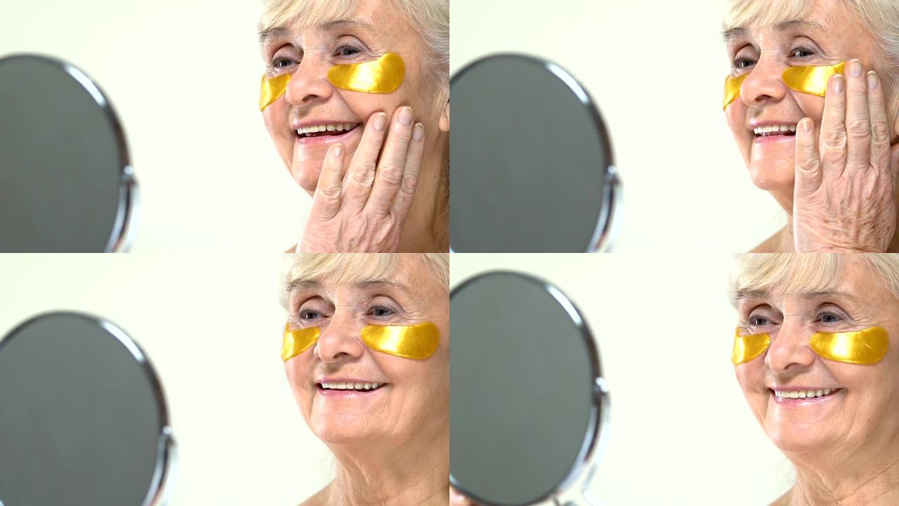 脸上有抗衰老水凝胶眼罩的高级女性照镜子