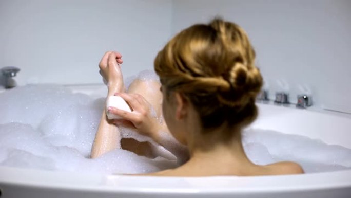 女性在洗澡时用洁面皂清洗身体，美容程序，后视图