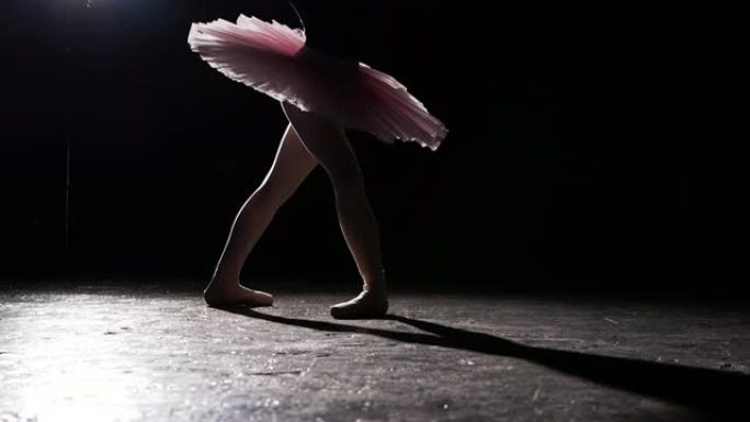 芭蕾舞女演员在演播室表演黑色背景的旋转木马。穿着芭蕾舞短裙和尖头鞋的女芭蕾舞演员。慢动作。