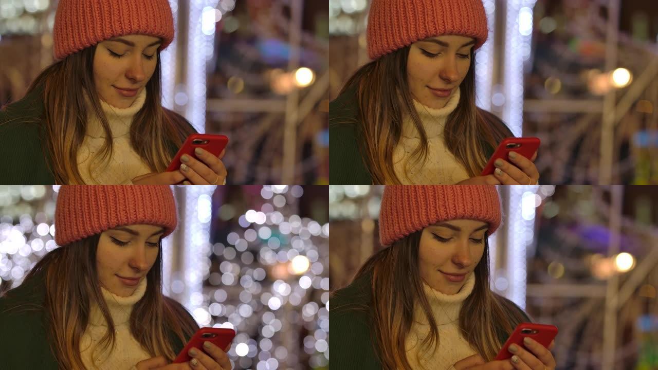 使用智能手机和微笑的冬装可爱的高加索女孩的特写镜头。年轻漂亮的女人在户外度过空闲时间。电影院4k P