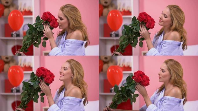 诱人的女人闻到一束红玫瑰，花束递送，情人节
