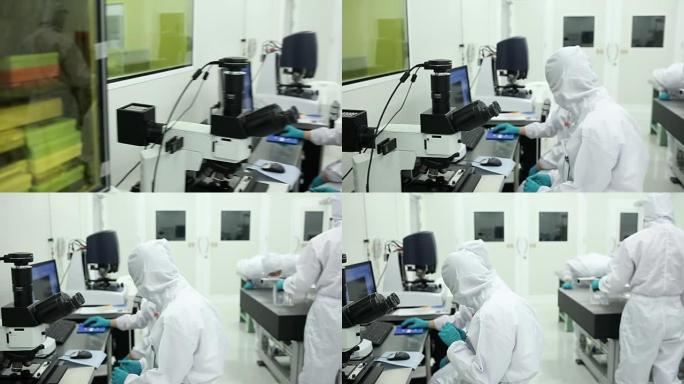 实验室洁净室里有显微镜的技术员