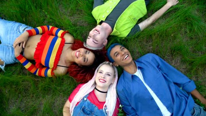 快乐的多种族朋友躺在公园的草地上，青年自由连接
