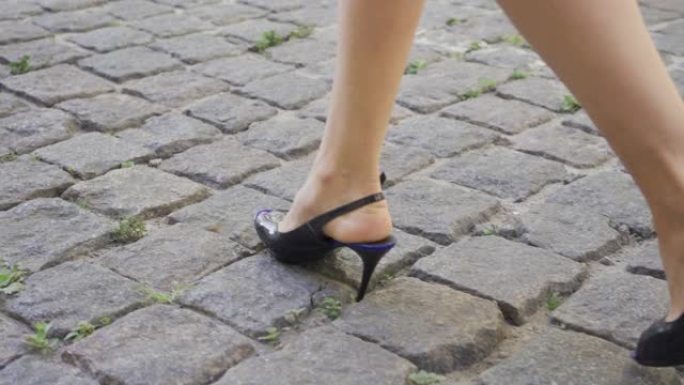 穿着时髦鞋子的女性腿走在街上。