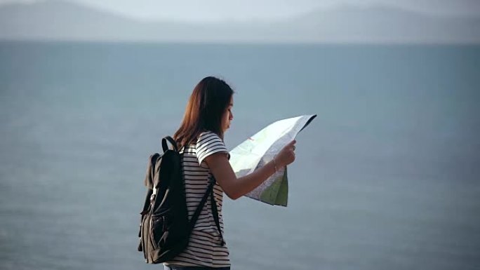 年轻女子带着地图在海滩上旅行。