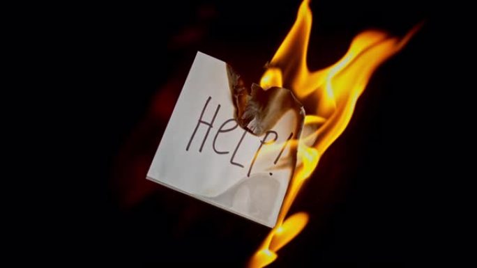 SLO MO LD白色的纸，上面刻有 “帮助!” 在火焰中燃烧