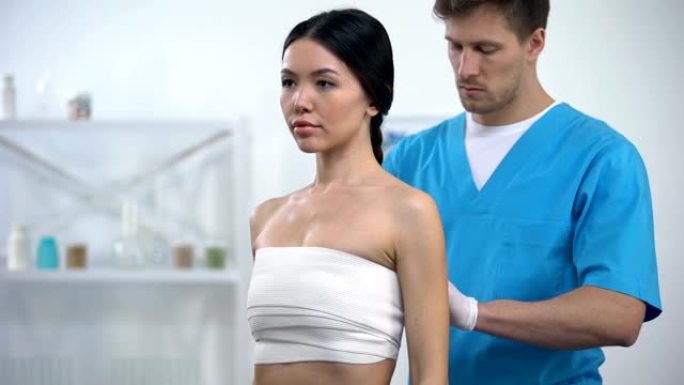 男性整形外科医生应用弹性贴合乳房女性患者，压缩