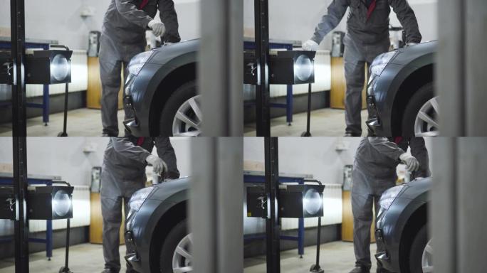 不可识别的男性汽车机械师用螺丝刀拧紧敞开式汽车发动机罩中的螺钉。男性专业维修工程师在修理厂调校或修理