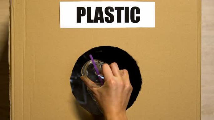 手工将一次性杯子放在带有塑料标志的废物篮中，分拣中心
