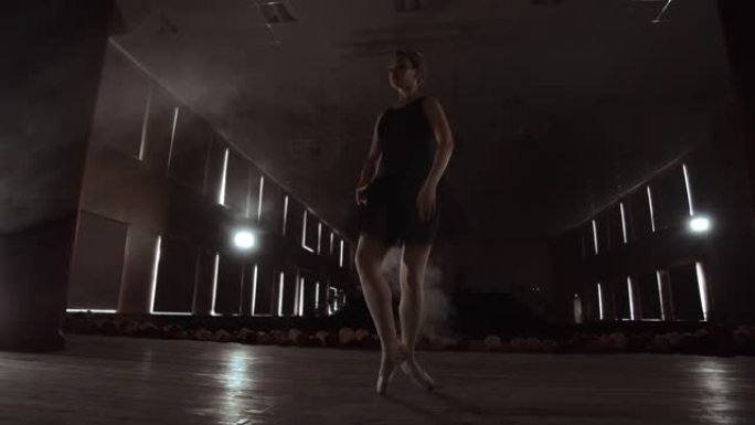 在聚光灯前慢慢跳舞的芭蕾舞演员。几个聚光灯显示了一个慢动作在黑暗舞台上跳舞的芭蕾舞演员。