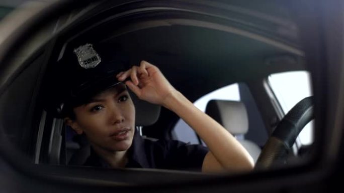 亚洲警官调整她的制服帽，看着后视镜