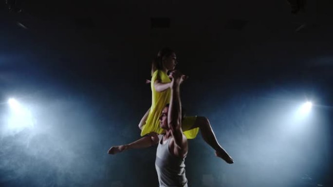 变焦相机，一名女舞者跳到她的伴侣肩膀上。舞台上的杂技舞蹈音乐剧。当代当代