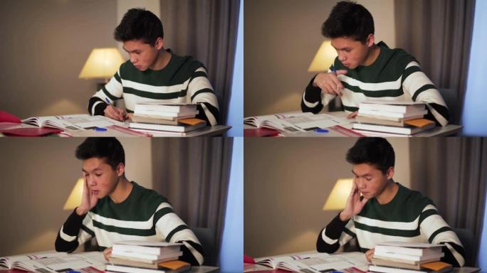 疲惫的亚洲大学生在家做作业的侧视图特写。年轻英俊的男孩晚上在室内的工作簿上阅读和写作。学习，教育，智