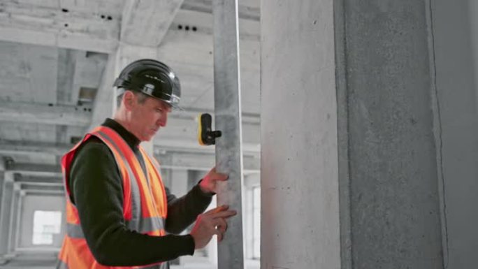 男建筑师测量工业建筑中的支撑梁并对其进行标记