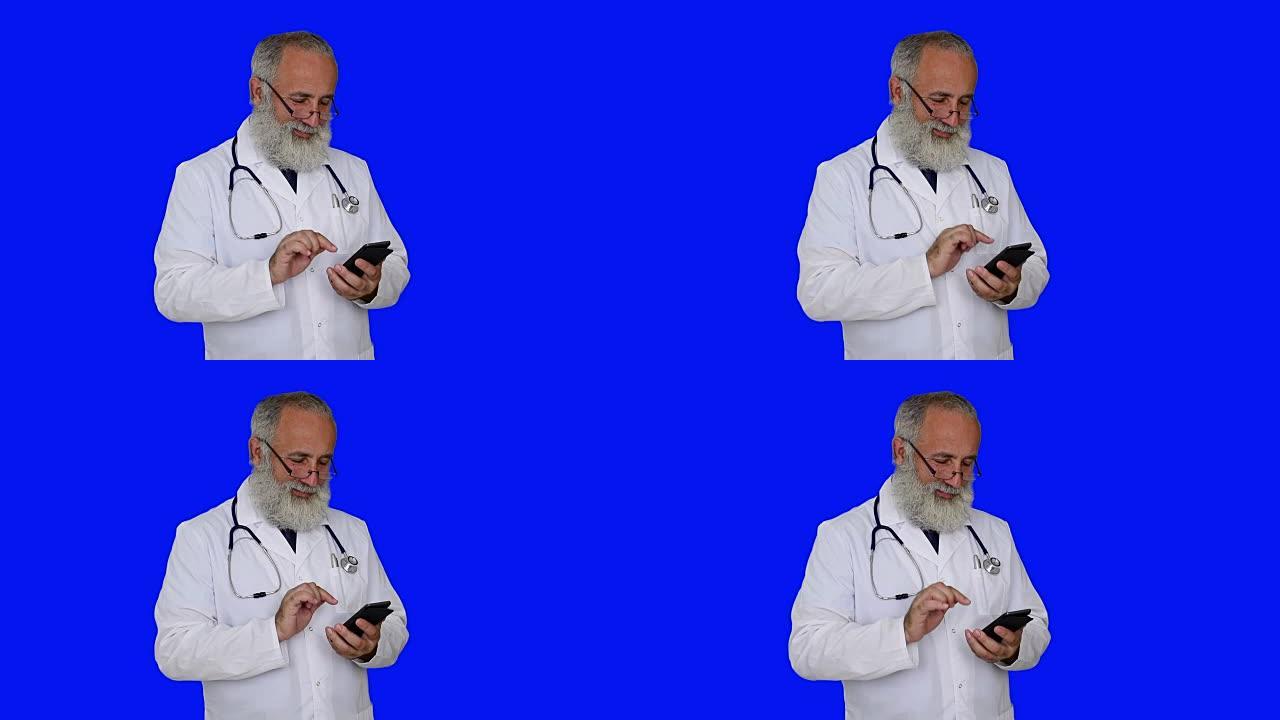 成人高级医生微笑并在蓝色背景上使用智能手机