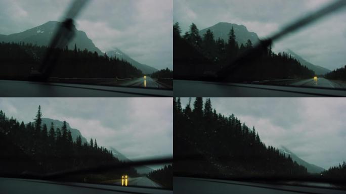 在加拿大艾伯塔省黄昏时分，贾斯珀国家公园被森林包围的加拿大落基山脉的潮湿高速公路上行驶时，挡风玻璃刮