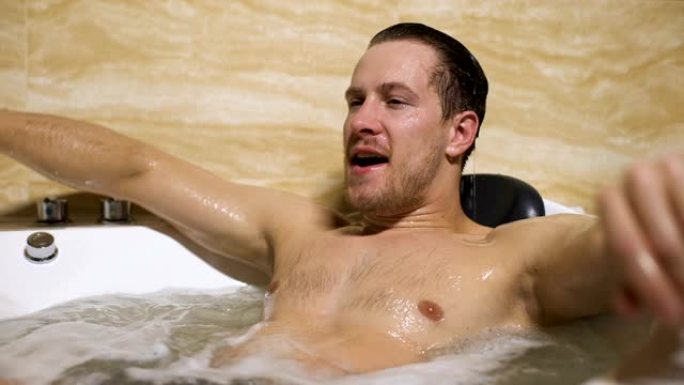 英俊的男人在洗澡时微笑，满意愉快的水疗程序