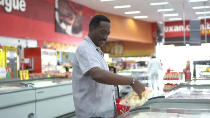 成熟的男人在超市冰柜中寻找和选择产品